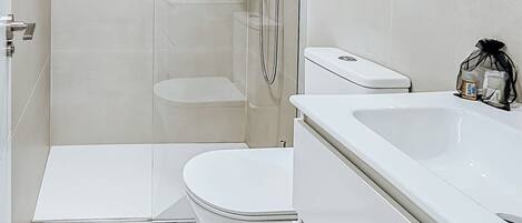 A modern bathroom with a glass-enclosed shower, a white toilet, and a large bathtub.