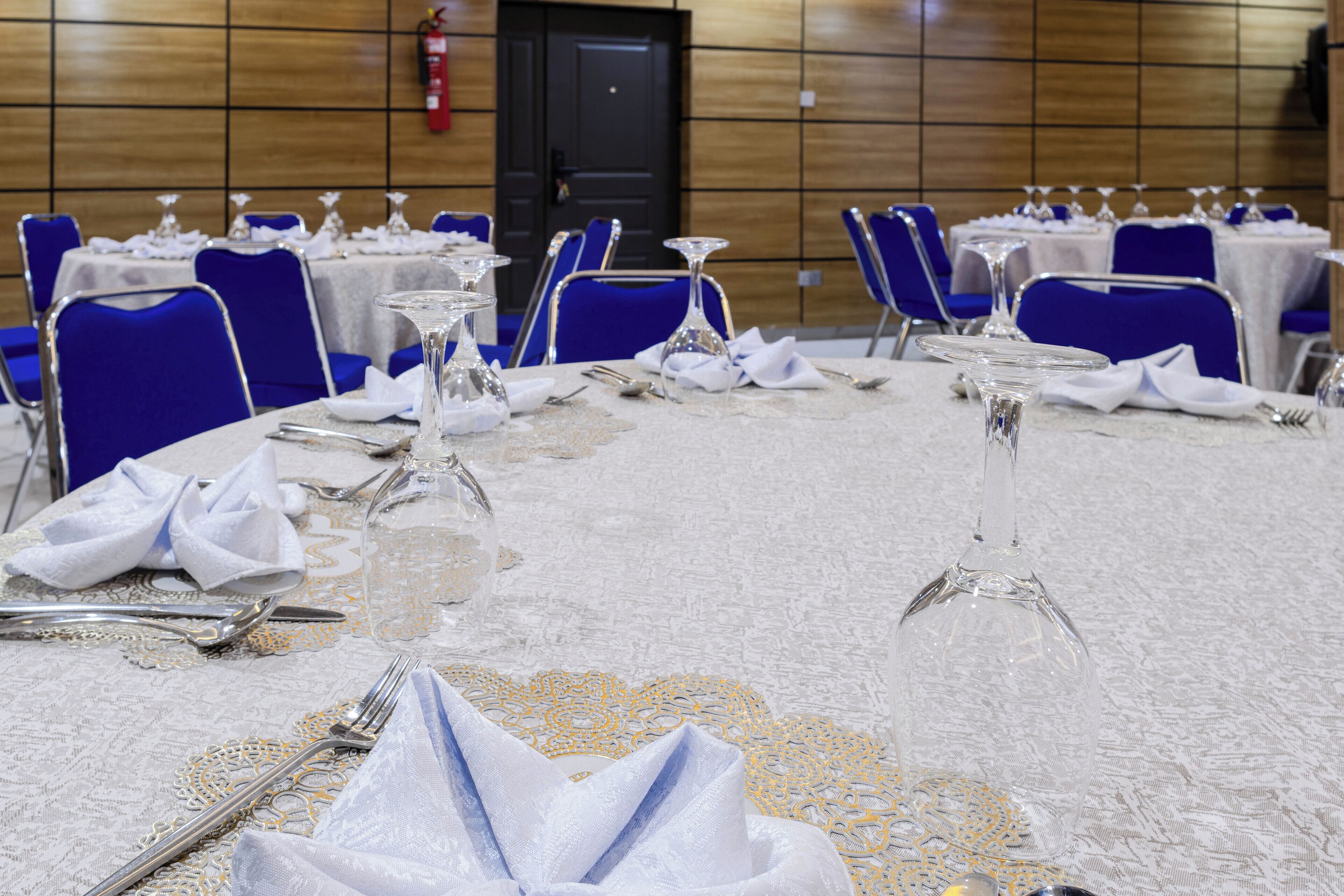 A banquet hall with tables set for a formal event, complete with fine china, silverware, and crystal glassware.
