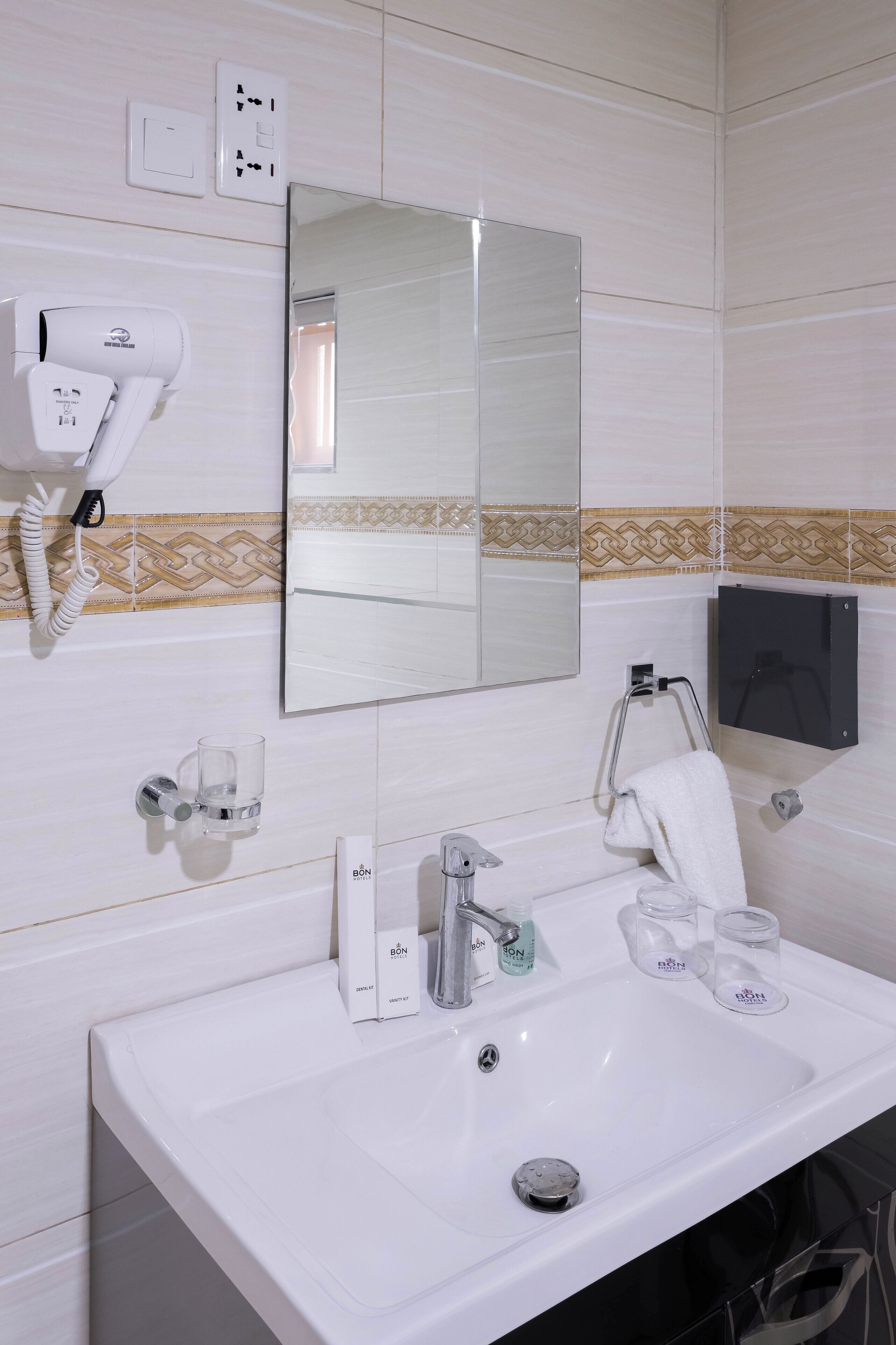 A bathroom with a white sink, a hairdryer, a mirror, and a towel rack.