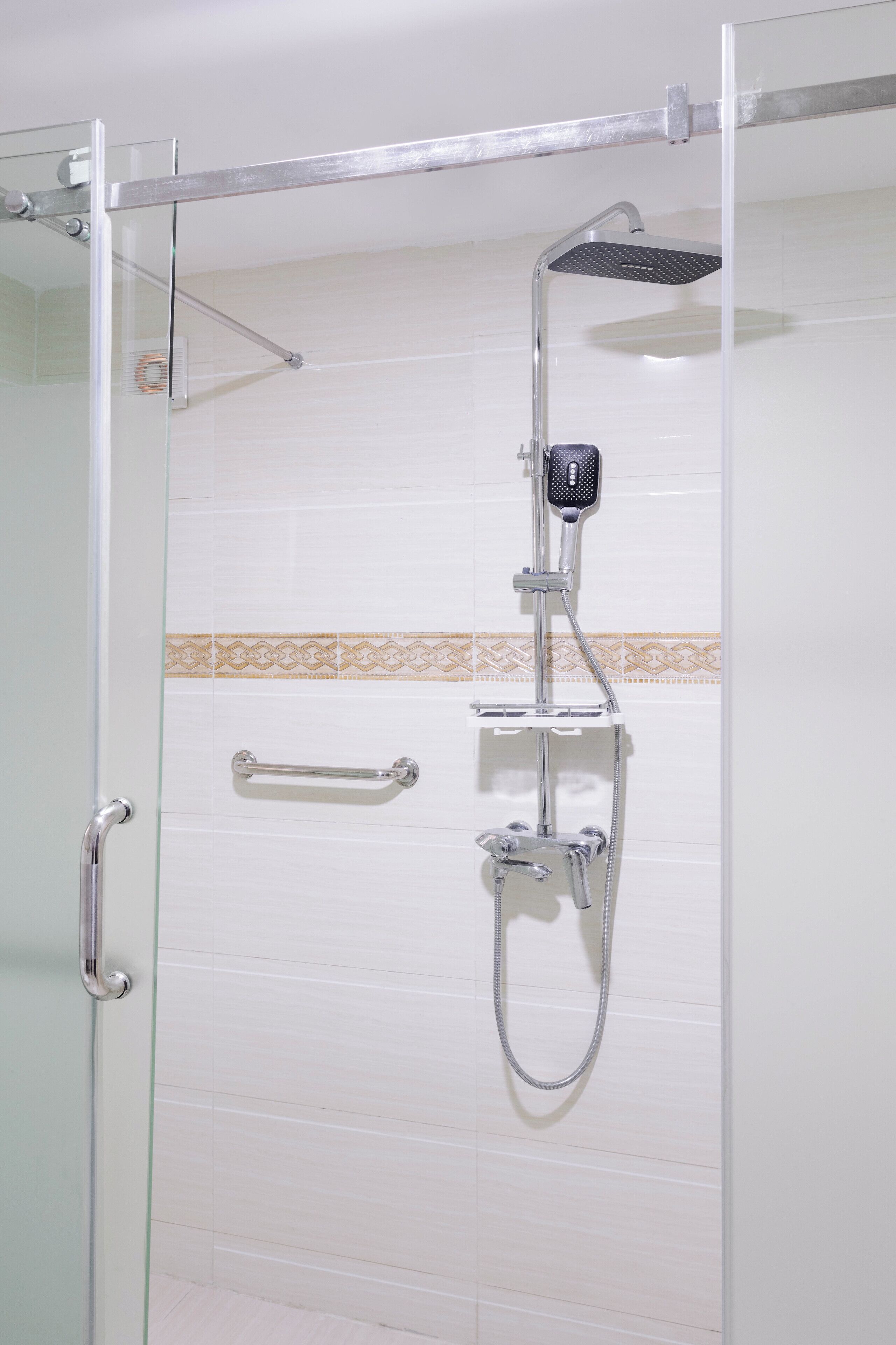 A glass-enclosed shower with a handheld showerhead and a fixed showerhead.