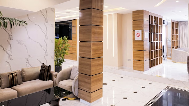A modern hotel lobby with a marble wall, a wooden column, a sofa, and a seating area. - BON Hotel Kabuwol (Ibadan)