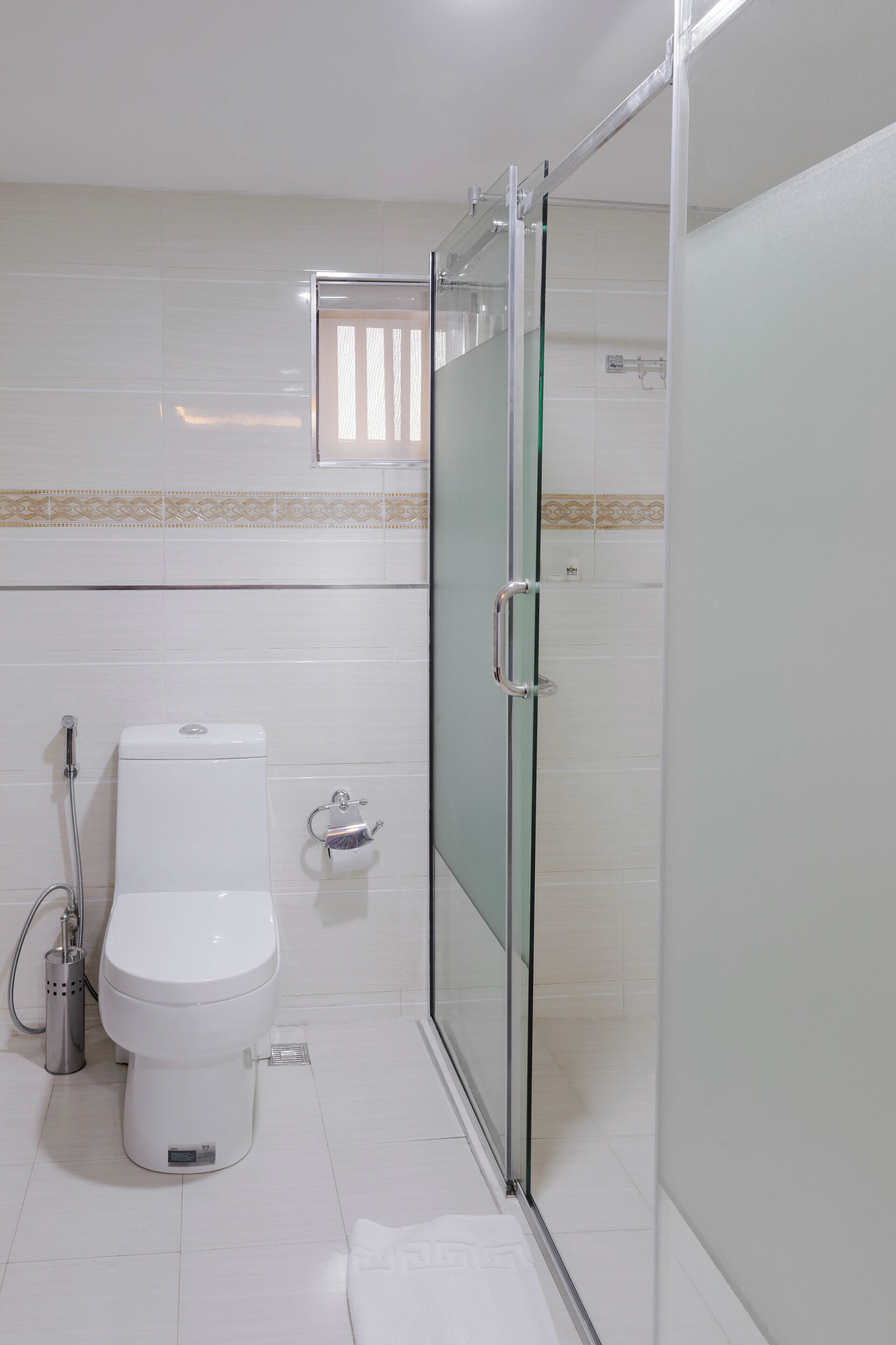 A modern bathroom with a glass-enclosed shower, a toilet, and a bidet.