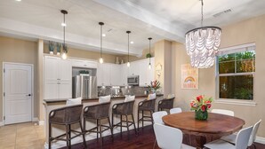 A modern kitchen with white cabinets, stainless steel appliances, and a central island with bar stools. - Kulalani at Mauna Lani Treasure w/ Beach Club Pass (Waimea)