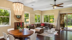 A spacious living area with a wooden dining table, white chairs, a brown sofa, and a ceiling fan. - Kulalani at Mauna Lani Treasure w/ Beach Club Pass (Waimea)