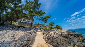 A coastal property with a rocky path leading to a house, surrounded by trees and overlooking the sea. - Villa Gardenal by Villas Guide (Blato)