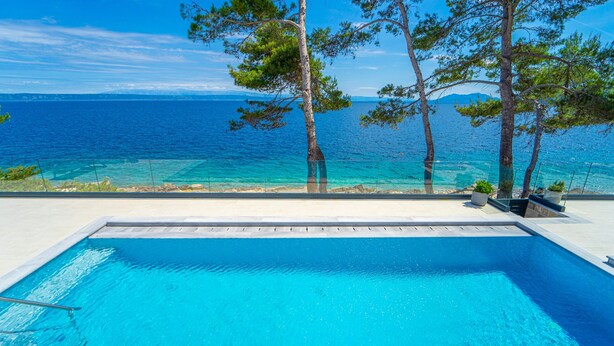 Une piscine avec vue sur la mer et les arbres.