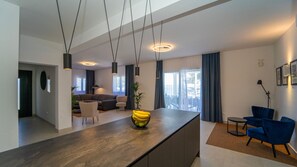 A modern living room with a sofa, a dining area with a table, and a kitchen with a counter. - Villa Gardenal by Villas Guide (Blato)
