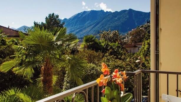 En balkon med udsigt over bjerge, frodig vegetation og en klar himmel.