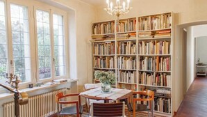 Et bibliotek med en stor reol, et bord med stole og en radiator.
