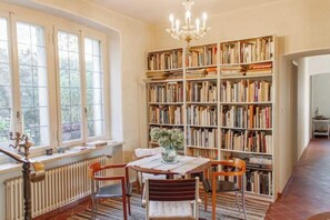 A library with a large bookshelf, a table with chairs, and a radiator. - Villa Dei Muralti, Exclusive Villa (Muralto)