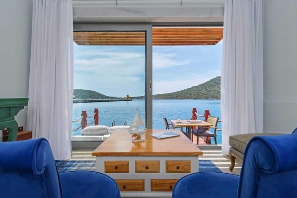 A room with a wooden table, blue chairs, and a view of the sea and hills. - The Doria Yacht Club Kas Hotel (Kaş)