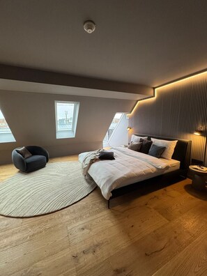 A modern bedroom with a bed, a chair, a round rug, and a skylight. - Conlon House Central (Munich)