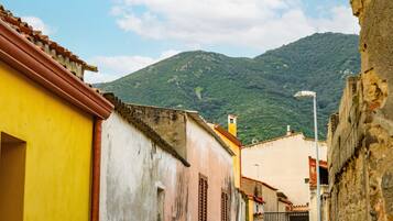 Uma rua estreita com edifícios, uma montanha ao fundo e um poste de luz.