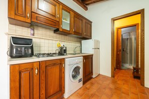 A kitchen with wooden cabinets, a washing machine, a stove, and a refrigerator.