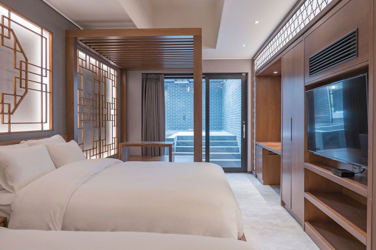 Una habitación de hotel moderna con una cama grande, un televisor y un balcón con vistas a la ciudad.