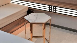 A modern room with a hexagonal marble table, a beige sofa, and wooden paneling with black and white decorative lighting. - Yeon Hwa Moon Hotel (Incheon)