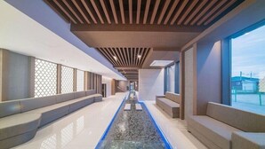 A modern hotel corridor with a long, narrow pool, seating areas on both sides, and large windows providing views. - Yeon Hwa Moon Hotel (Incheon)