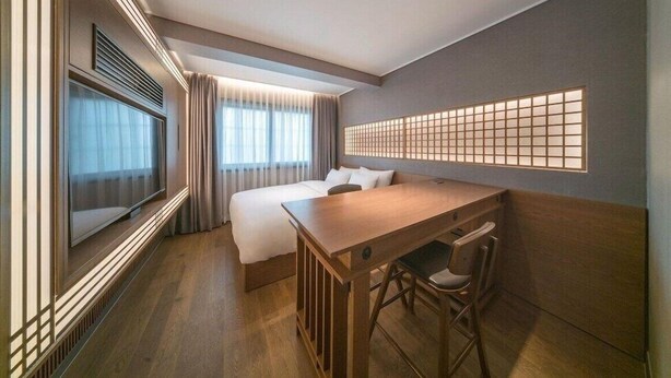 A hotel room with a bed, a desk, a chair, a TV, and a decorative wall panel. - Yeon Hwa Moon Hotel (Incheon)