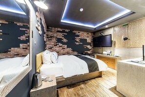 A modern hotel room with a brick-patterned wall, a flat-screen TV, a wooden headboard, and a wooden floor. - Duruwa Hotel (Incheon)