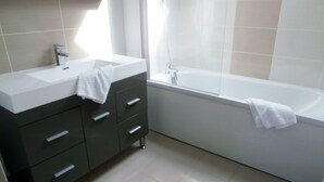 Ein modernes Badezimmer mit einem weißen Waschbecken, einem dunklen Waschtisch und einer Badewanne.