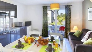 Eine moderne Küche mit Essbereich, einer Couch und Blick ins Freie.