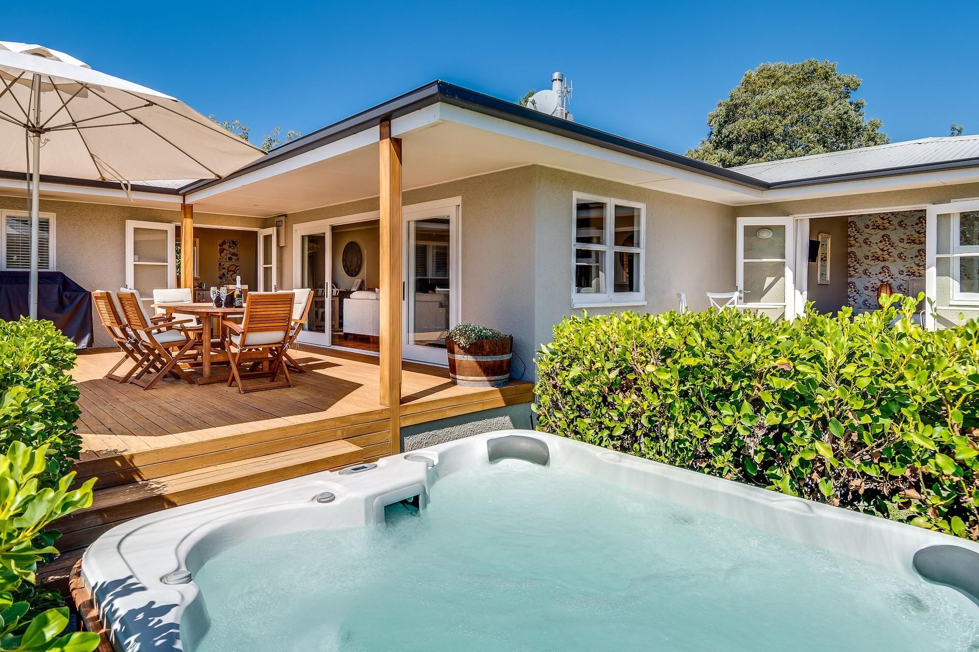 Una casa con patio, jacuzzi y zona de estar techada al aire libre.