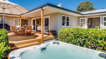 Una casa con patio, jacuzzi y zona de estar techada al aire libre.