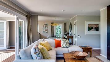 Una sala moderna con un amplio sofá modular, una mesa de centro de madera y un comedor con mesa y sillas.