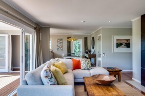 Uma sala de estar moderna com um amplo sofá modular, uma mesa de centro de madeira e uma área de jantar com mesa e cadeiras.