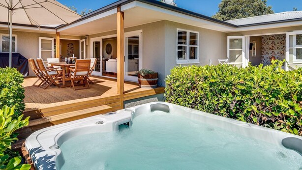 A house with a patio, a hot tub, and a covered outdoor seating area. - The Farmhouse At Mission Estate (Napier)