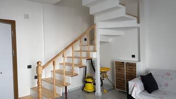 Eine Treppe mit hölzernen Geländern, ein gelber Staubsauger, ein Sofa mit Blumenmuster und ein Holzschrank.