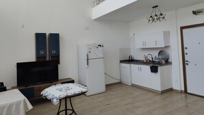 A compact kitchen with white cabinets, a refrigerator, and a dining area with a table and chairs. - 2-bedroom apartment in perfect Erdemli with air conditioning (Erdemli)