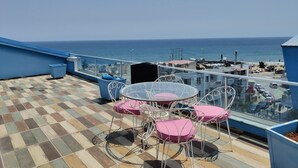 A terrace with a checkered floor, a table with pink cushions, and a view of the sea. - 2-bedroom apartment in perfect Erdemli with air conditioning (Erdemli)