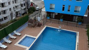 Une piscine sur le toit, offrant une vue sur la mer et entourée d’immeubles d’habitation.
