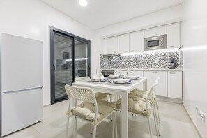 A modern kitchen with white cabinetry, a microwave, and a tiled backsplash. - Correeira Luxury Residence B (Albufeira)