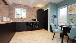 Une cuisine compacte équipée d’un lave-vaisselle, d’un four à micro-ondes et d’un évier. Un coin repas avec une table et des chaises est également disponible.