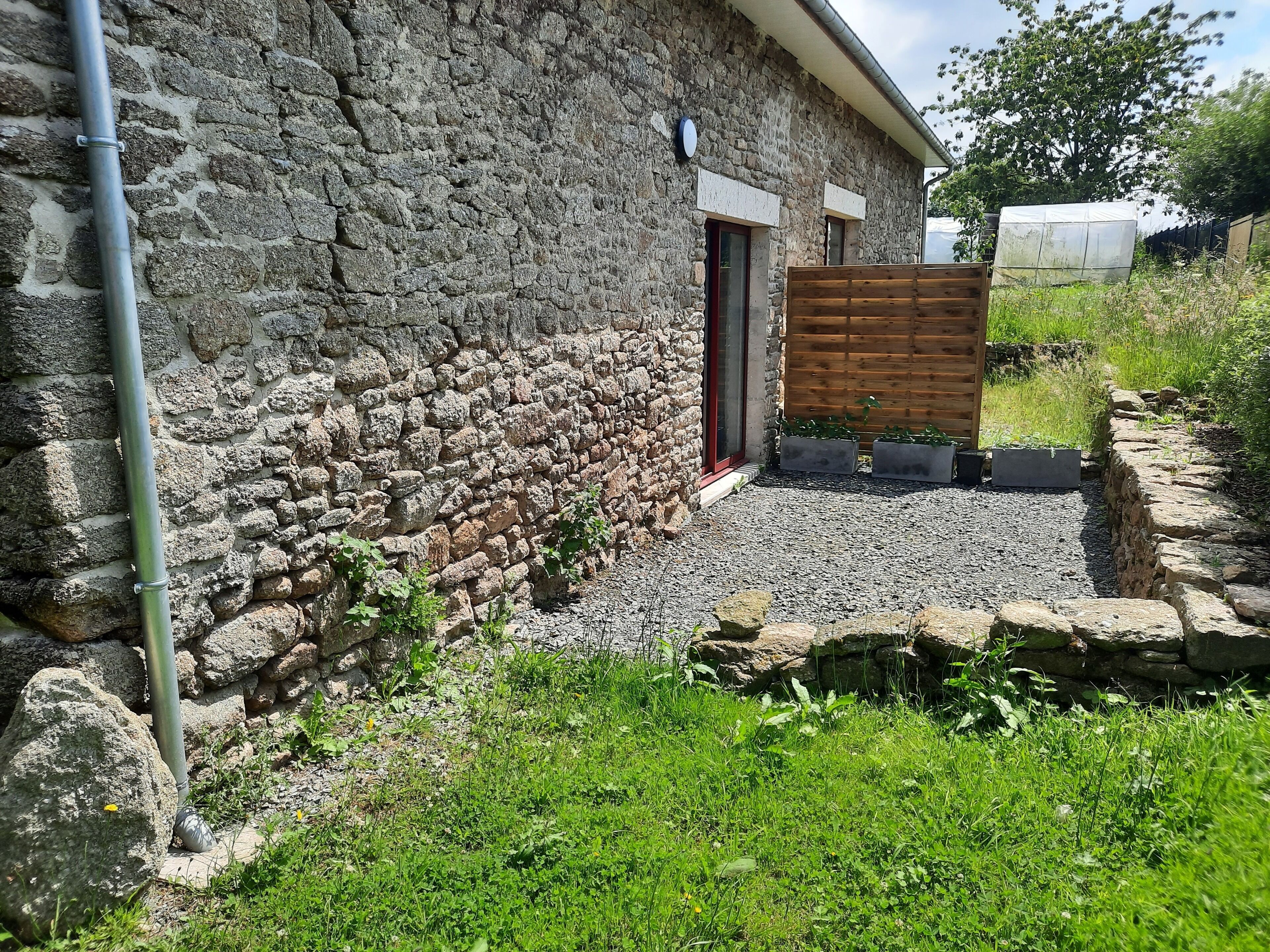 A stone building with a wooden door and a small garden area with gravel and plants.