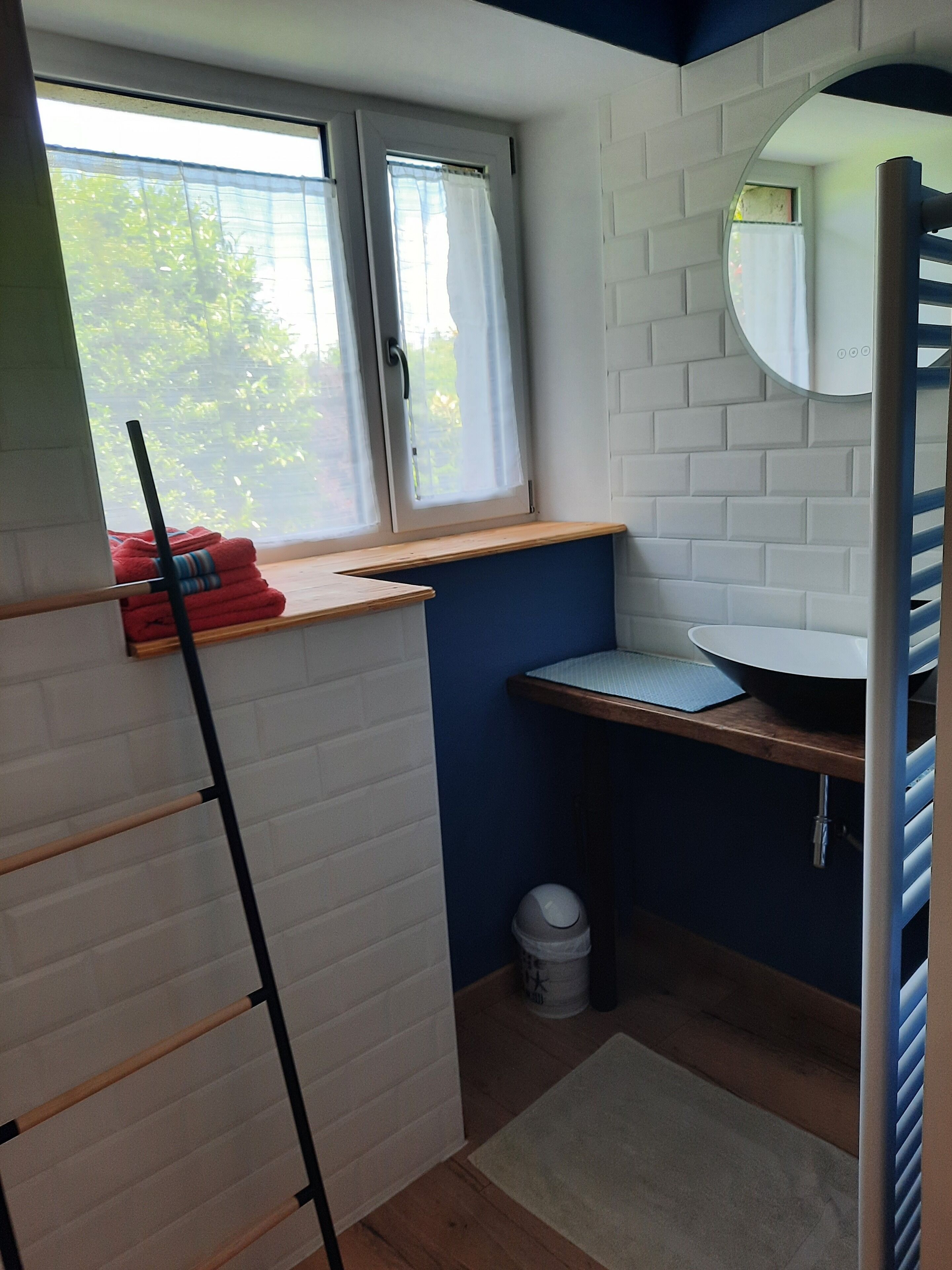 A small bathroom with a window, a sink, and a mirror.
