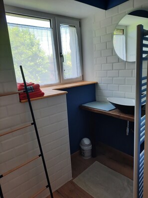 Ein kleines Badezimmer mit Fenster, Waschbecken und Spiegel.