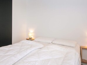 A bed with white bedding, a bedside lamp, and a wooden nightstand. - 5 Star Holiday Home in Aabenraa (Aabenraa)