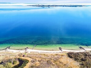 An aerial view of a coastal area with a clear blue sea, a sandy beach, and a small island in the distance. - 5 Star Holiday Home in Aabenraa (Aabenraa)