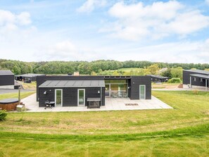 A modern building with a flat roof, large glass windows, and a patio area with outdoor seating. - 5 Star Holiday Home in Aabenraa (Aabenraa)
