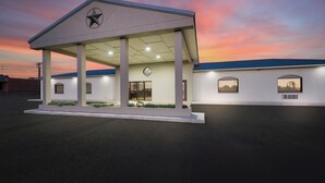 A building with a covered entrance, columns, and a clock. - Red Roof Inn Nacogdoches (Nacogdoches)