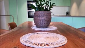 A wooden dining table with a woven placemat and a potted plant. - Cavigliano Rustic (Cavigliano)