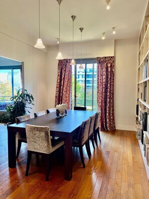 A dining area with a large wooden table, four chairs, and pendant lights. - Chic and spacious haven of calm in Neuilly (Neuilly-sur-Seine)