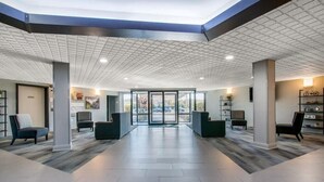 A spacious lobby with a high ceiling, a central glass door entrance, and seating areas on either side. - Quality Inn Carlisle (Carlisle)