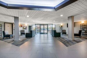 En rymlig entréhall med högt i tak, en receptionsdisk och sittgrupper.