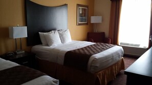 A hotel room with a large bed, a desk, a chair, a lamp, and a window with curtains. - Towanda Inn Formerly Best Western Plus Towanda Inn (Towanda)