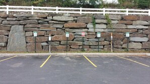 Un estacionamiento con un muro de piedra y una valla blanca.