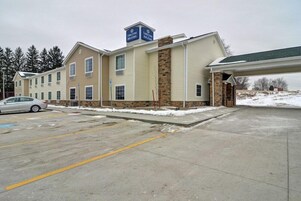 Hotel com estrutura em dois andares, área de estacionamento coberta e terreno coberto de neve.
